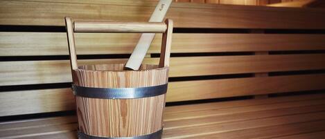 Un banco de madera con un balde de metal que contiene un palo de madera.