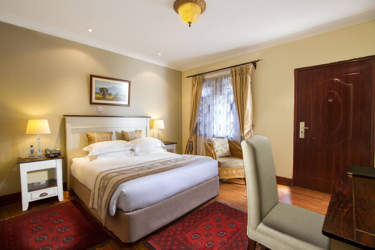 Ein Hotelzimmer mit einem großen Bett, einem Sessel, einem Schreibtisch und einer Tür.