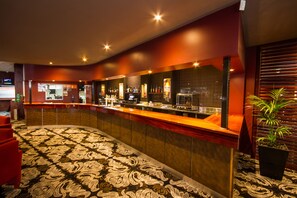 A hotel lobby with a curved reception desk, a patterned carpet, and a potted plant. - Wiley Park Hotel (Wiley Park)