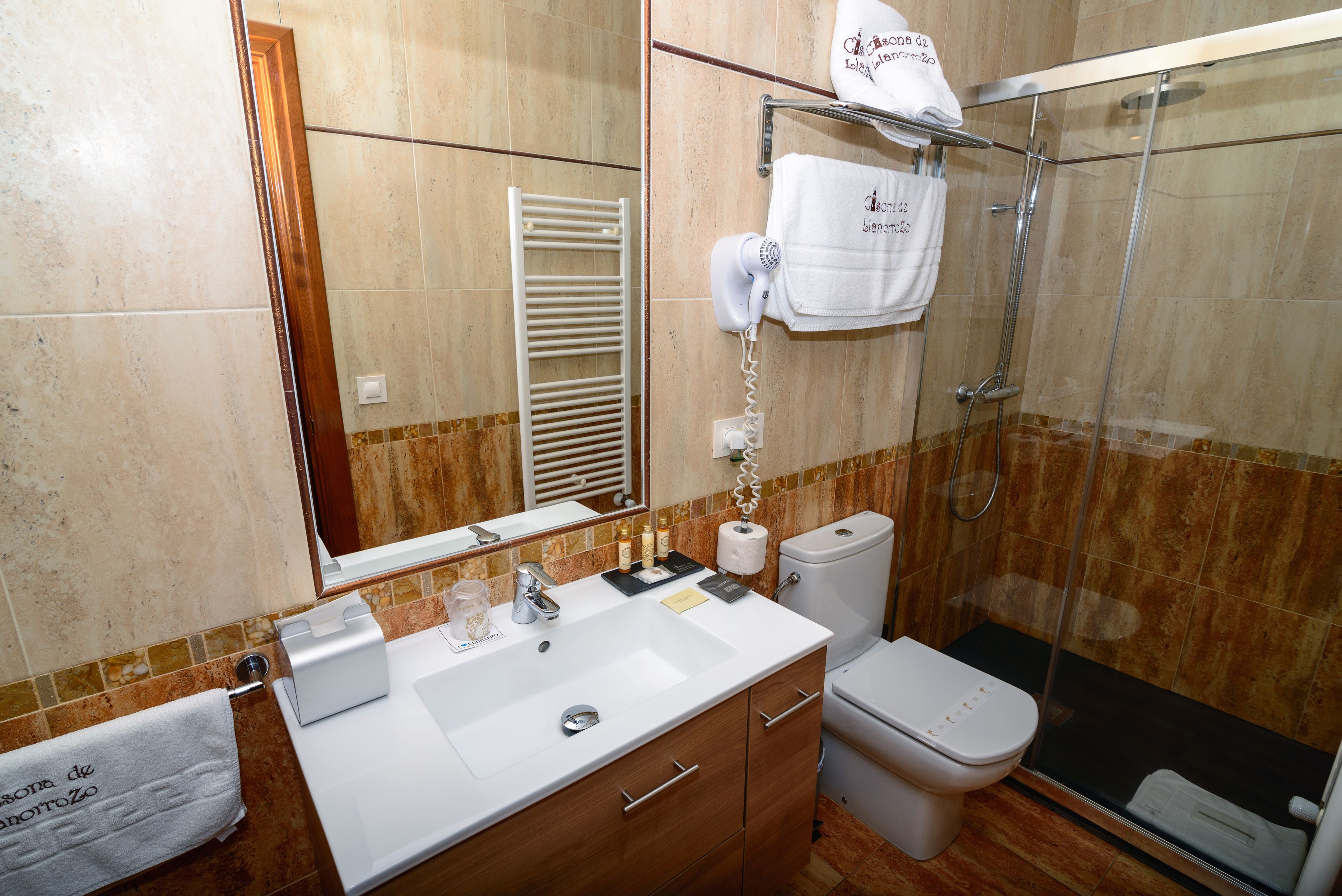 A bathroom with a white sink, a mirror, a towel rack, a toilet, and a shower area.