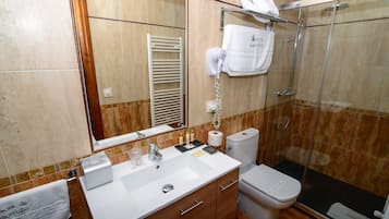 A bathroom with a white sink, a mirror, a towel rack, a toilet, and a shower area.