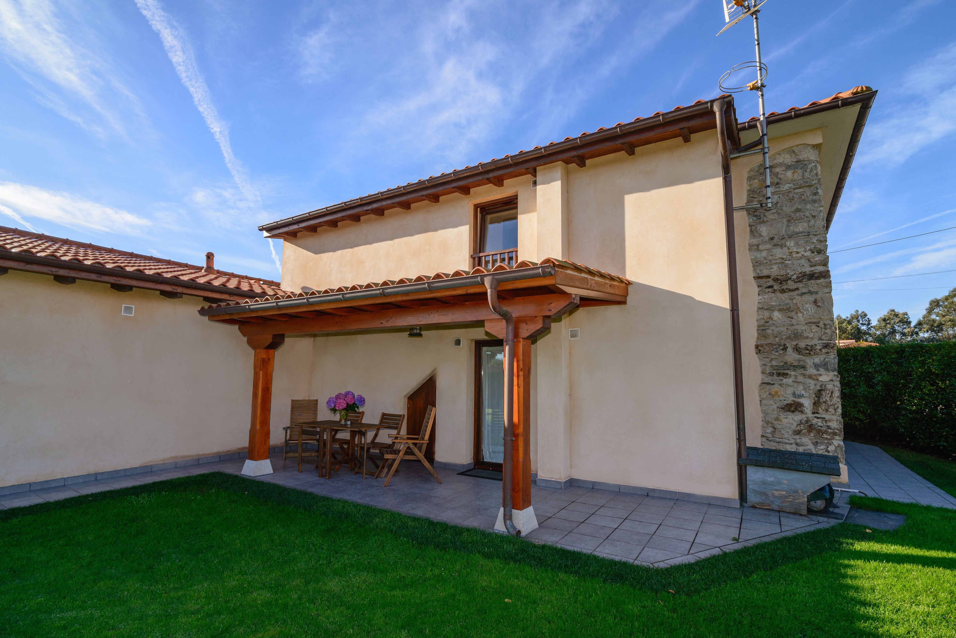 Ein Haus mit überdachter Terrasse, Steinpfeiler und einem Ziegeldach.