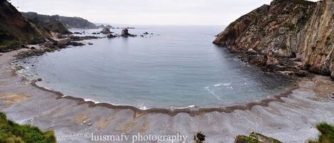 A coastal landscape with rocky cliffs and a sandy beach.