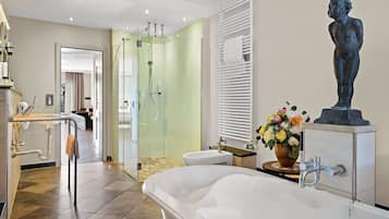 Ein modernes Badezimmer mit einer Glasdusche, einer freistehenden Badewanne und einem Waschbecken auf Säule.