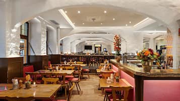A restaurant with wooden tables and chairs, a bar area, and a modern ceiling design.