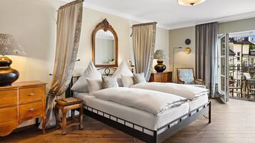 A bedroom with a double bed, a wooden nightstand, a dresser, a mirror, and a view of the balcony.