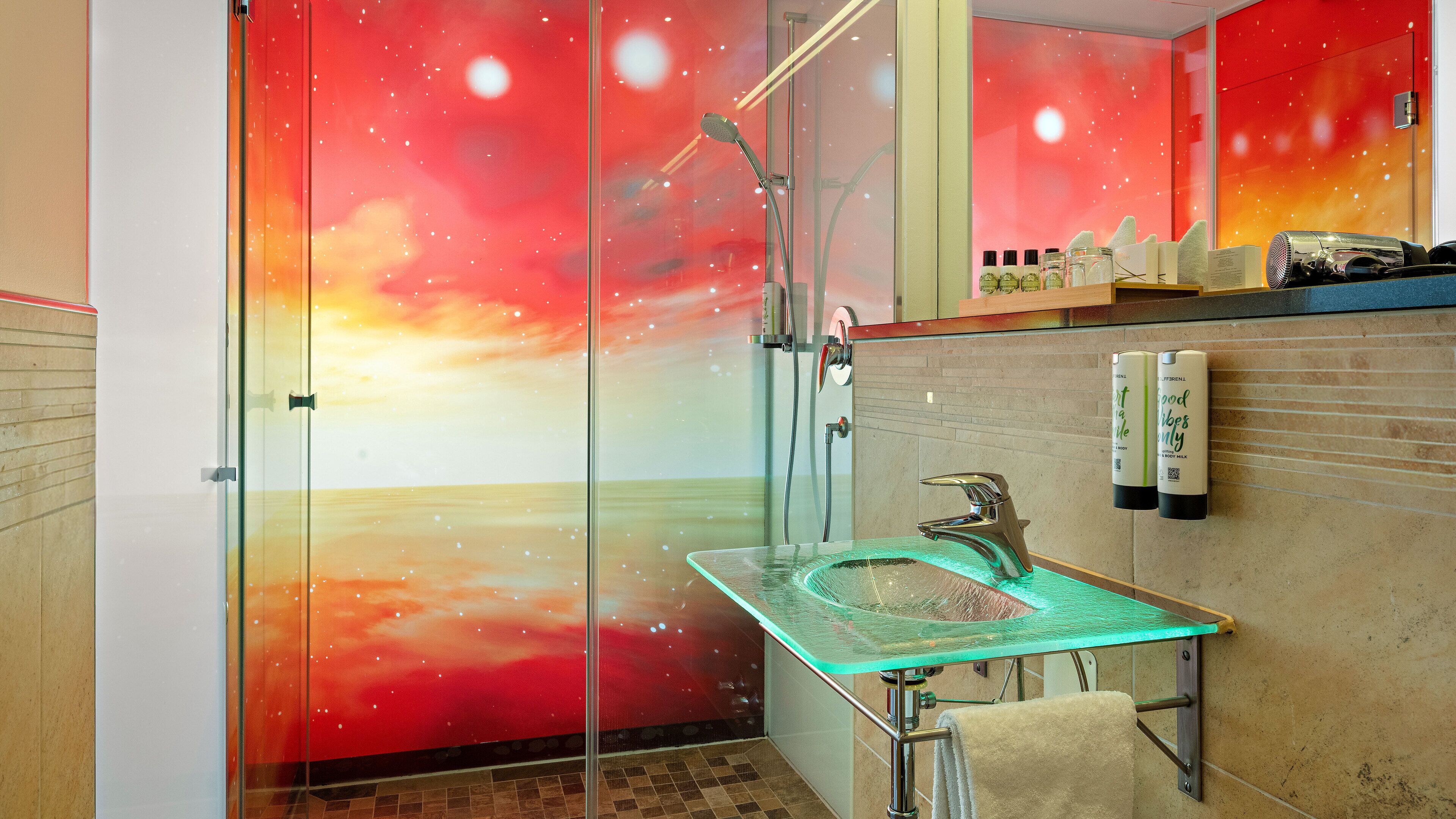 Ein Badezimmer mit Duschkabine aus Glas, Waschbecken aus Glas und einem Handtuchhalter.