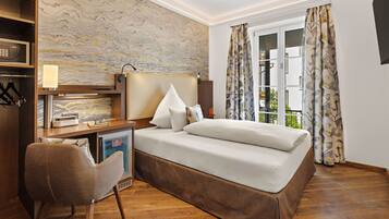 Un dormitorio con cama, mesita de noche, lámpara, silla y vistas al exterior.