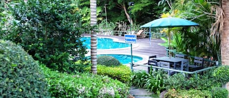 Una piscina al aire libre, sillones reclinables de piscina
