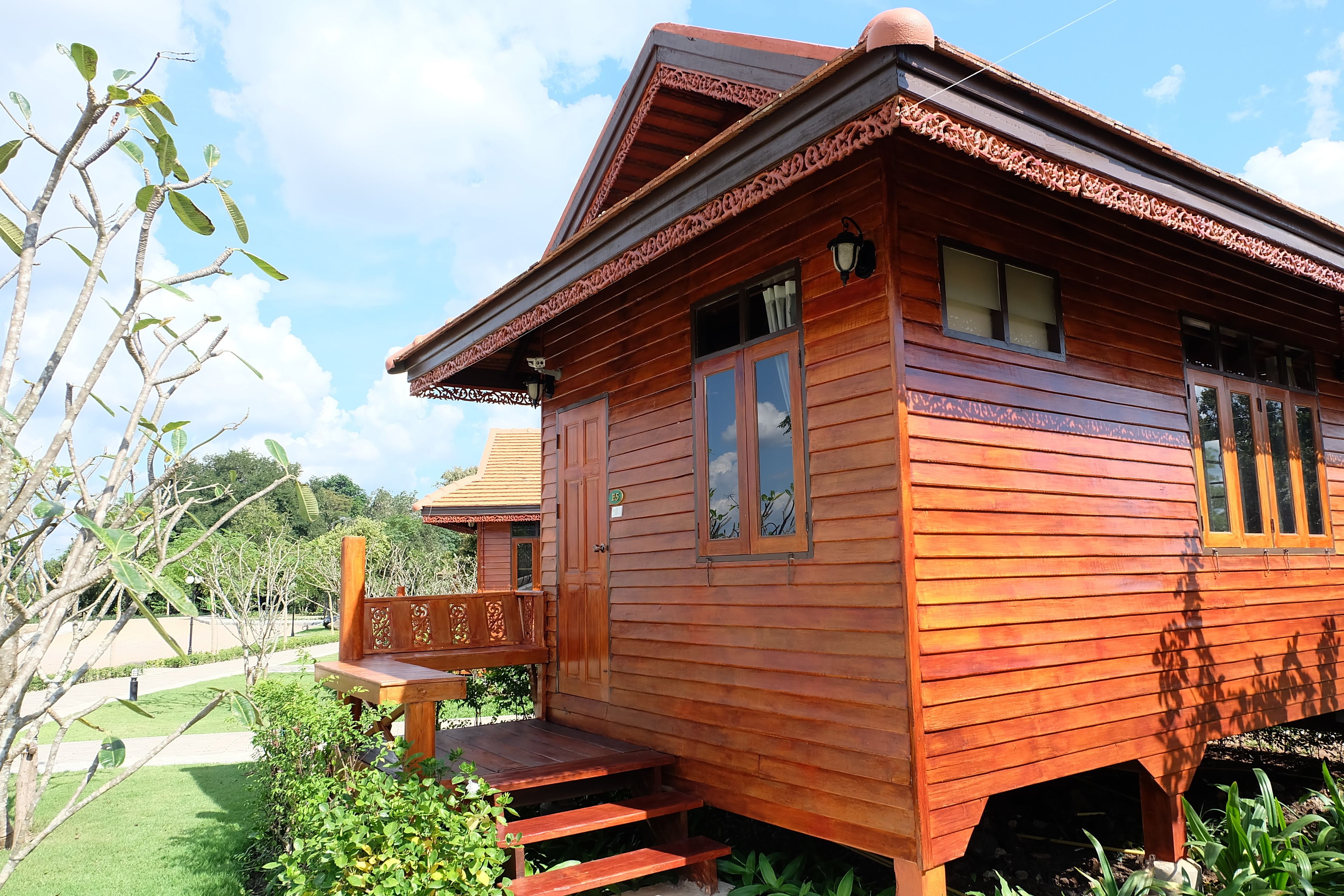 A wooden cabin with a porch, steps leading to the entrance, and a small garden area.