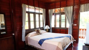 Una habitación de madera con una cama, una lámpara y cortinas.