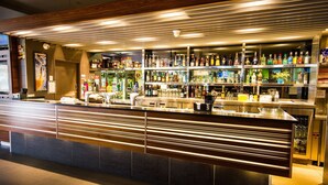 Una zona de bar con mostrador, estantes llenos de botellas y paneles de madera.