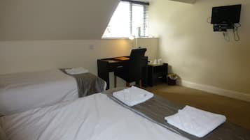 A hotel room with two beds, a desk, a chair, a TV, and a window with blinds.