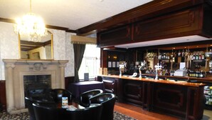 A bar area with a fireplace, bar counter, and seating. - Maes Manor Hotel (Blackwood)