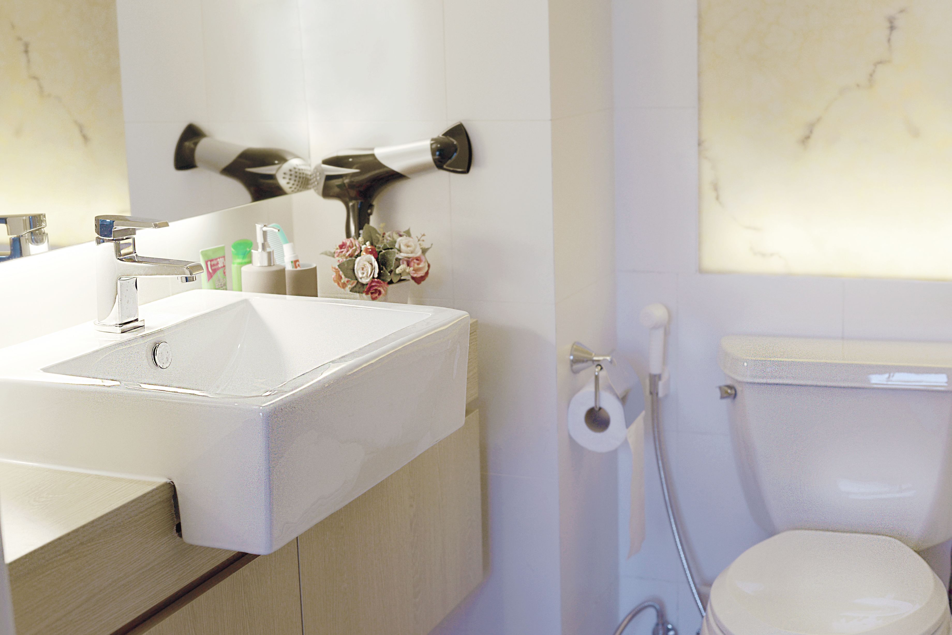 A bathroom with a white sink, mirror, and toilet.