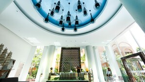 A spacious lobby with a high ceiling, a decorative ceiling light fixture, a reception desk, and a view of the outdoors through large windows. - Atlantis Condo Resort by Natnarin (Pattaya)