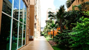 A corridor with glass walls, a wooden floor, and lush greenery. - Atlantis Condo Resort by Natnarin (Pattaya)
