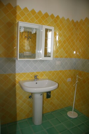 A bathroom with yellow diamond-patterned tiles, a white sink, and a mirror above it.