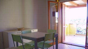 A small dining area with a table and four chairs, a white cabinet, and a basket on the cabinet. - Residenza Zodiaco (Santa Teresa di Gallura)