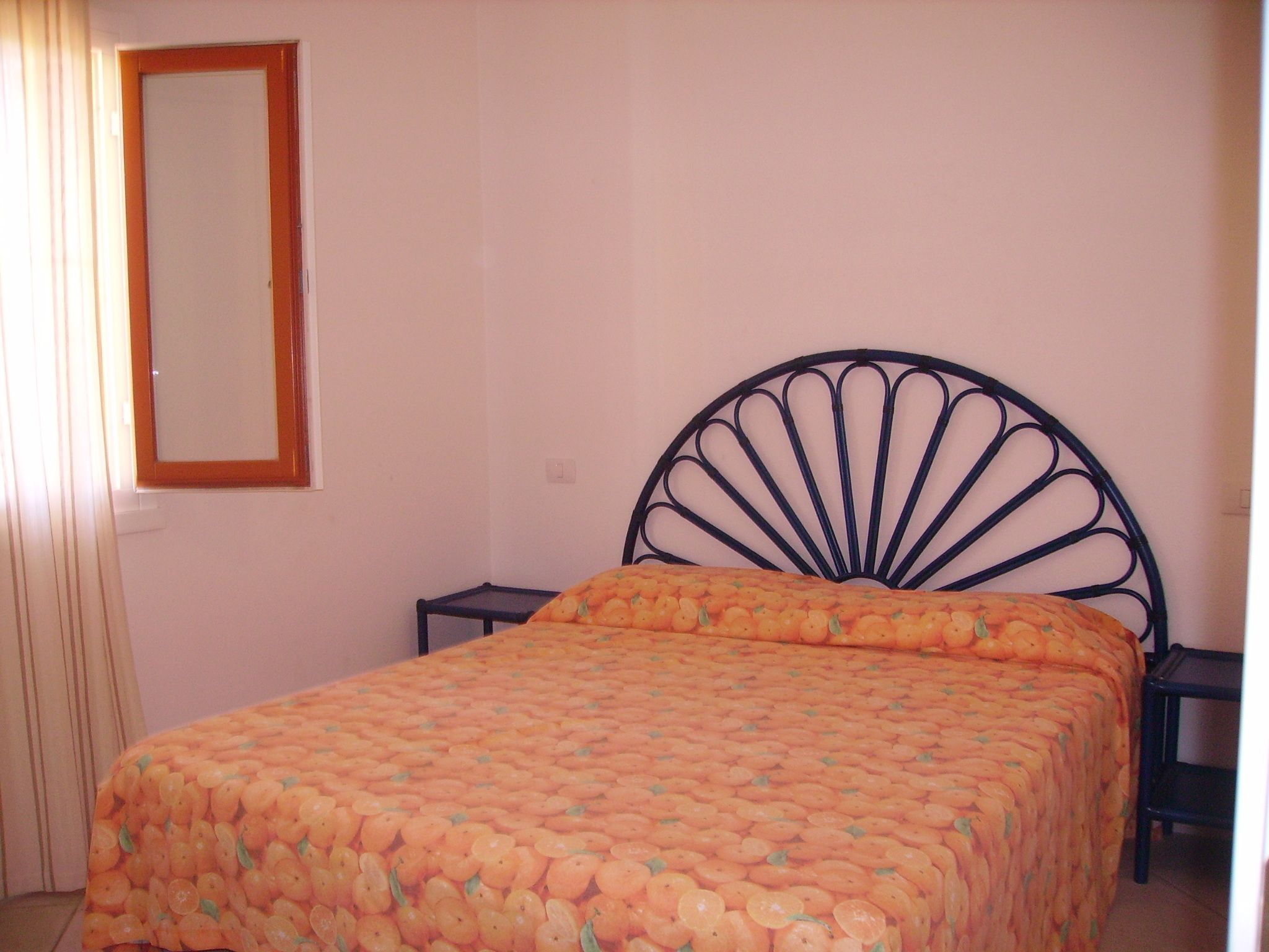 A bedroom with a bed, a nightstand, a chair, and a mirror on the wall.