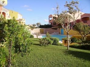 A pool area with lounge chairs, surrounded by well-maintained grass and trees.