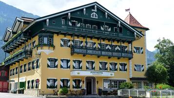 Ein traditionelles österreichisches Posthotel mit klassischer Fassade, mehreren Balkonen und Bergblick.