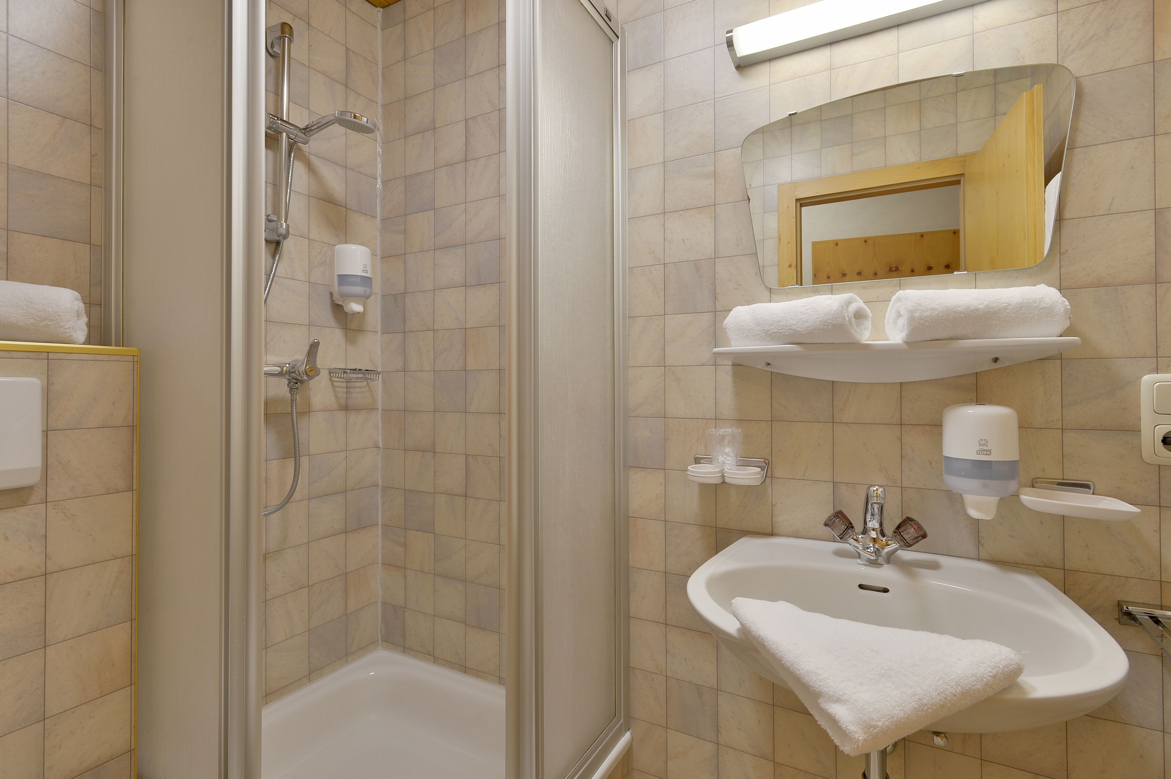 Un baño con ducha, lavamanos y espejo.