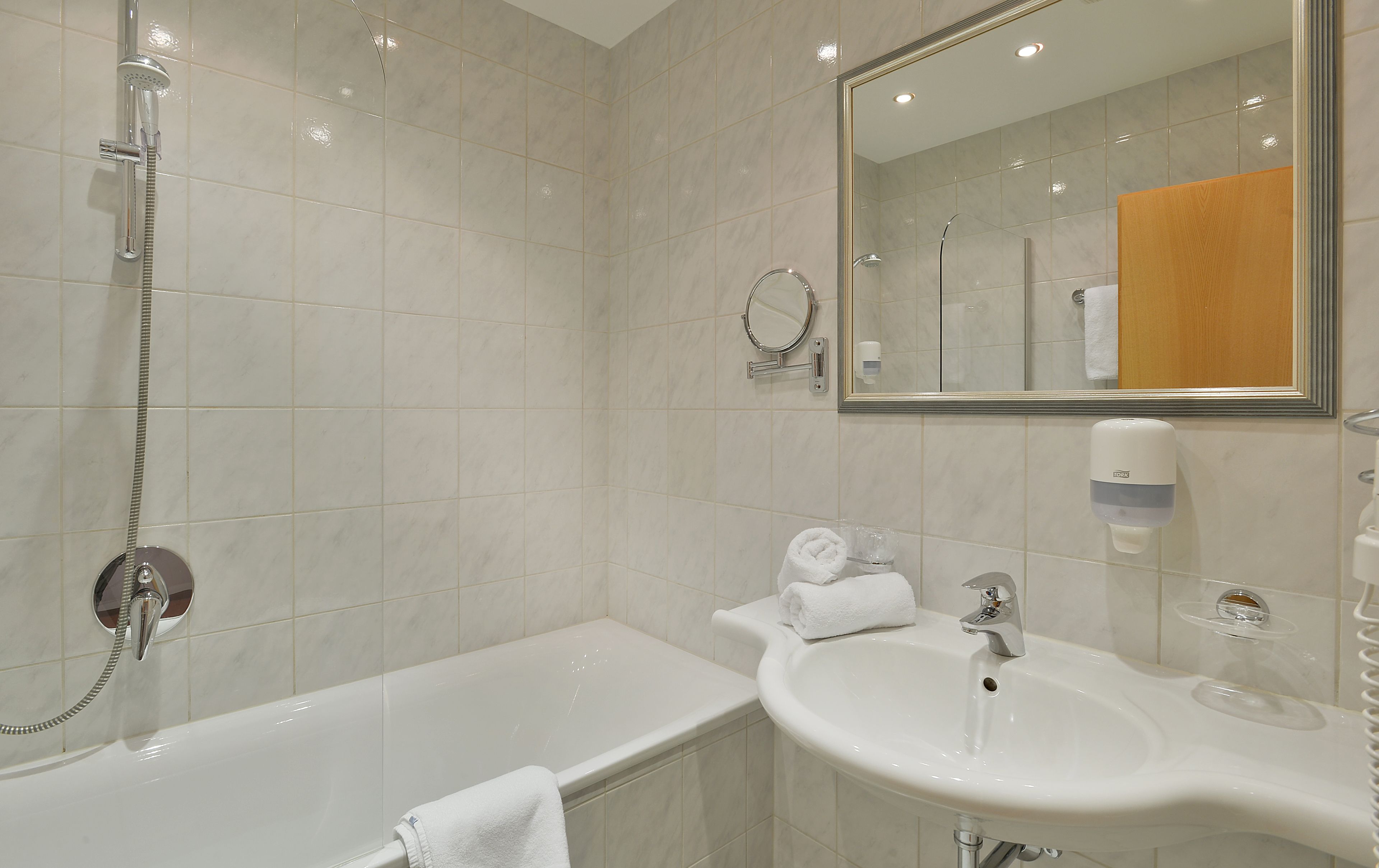 Ein modernes Badezimmer mit Badewanne, Waschbecken, Spiegel und Dusche.