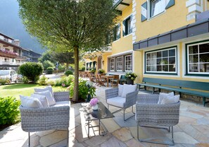 An outdoor seating area with wicker furniture, a table, and a potted plant. - Posthotel Mayrhofen (Mayrhofen)