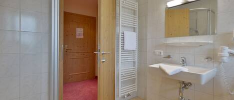 Un bagno con un lavandino bianco, uno specchio e un porta asciugamani.