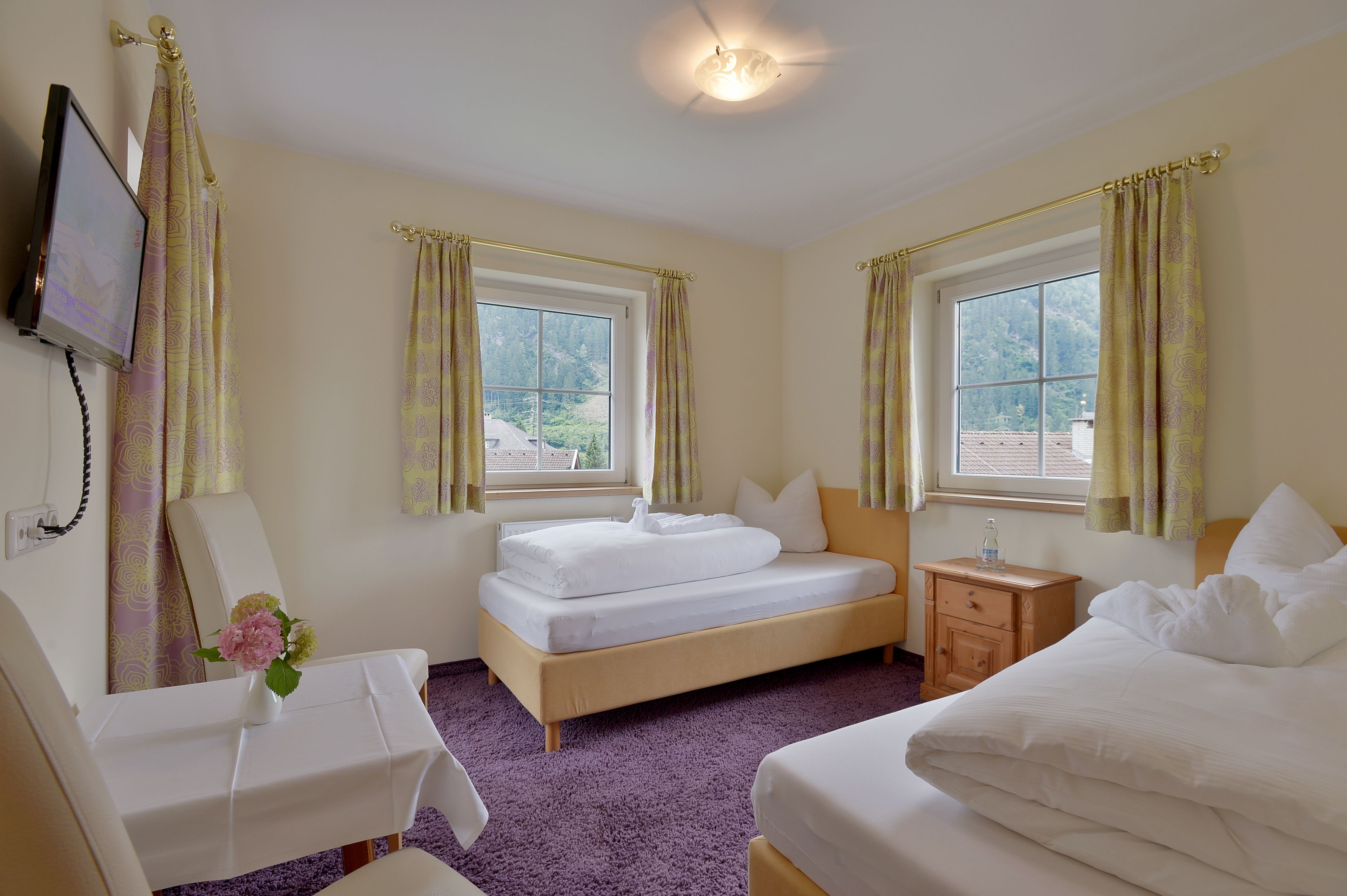 A hotel room with two beds, a desk, and a TV.