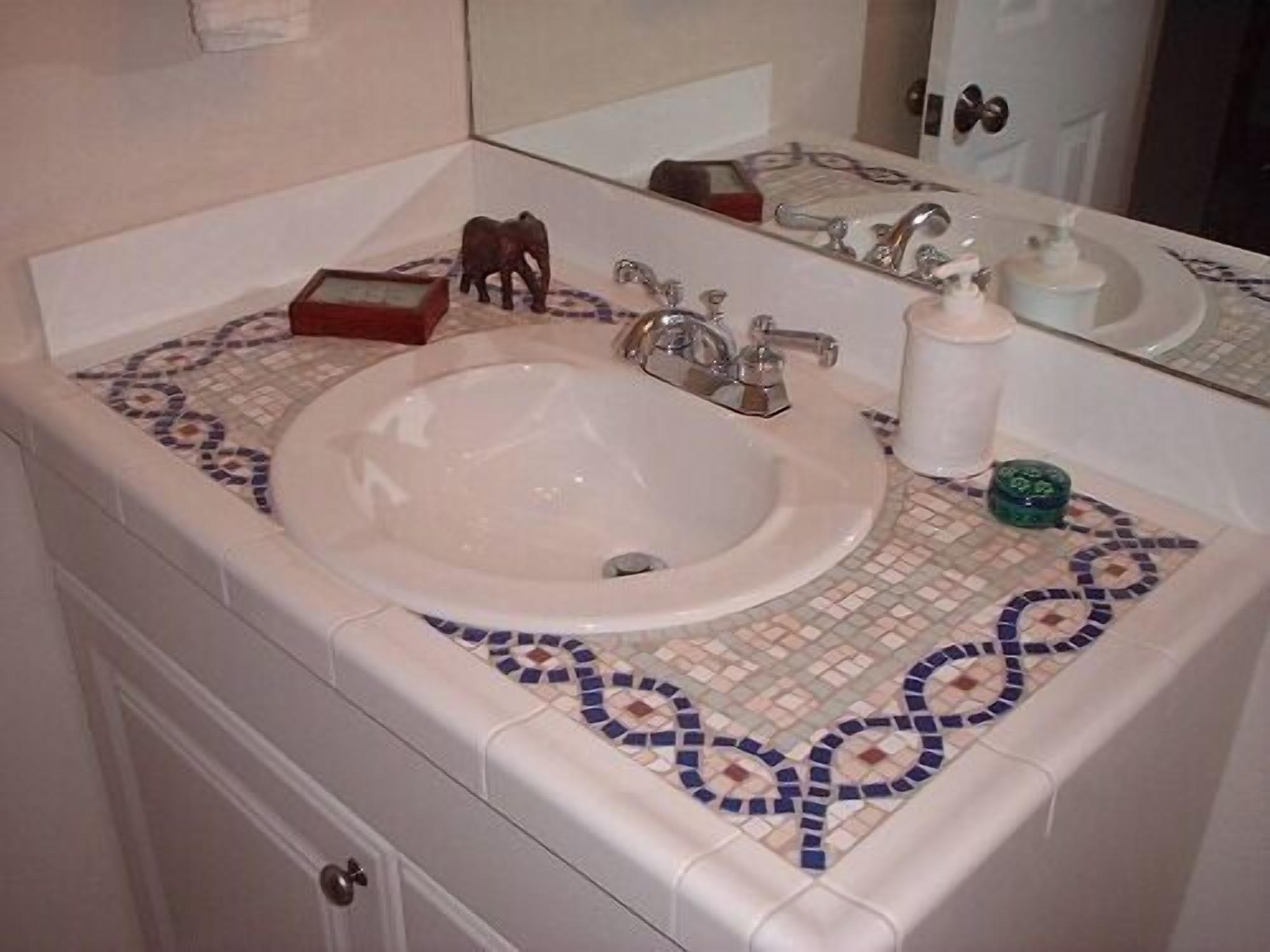 Un baño con lavamanos blanco, un espejo y salpicadero de azulejos.