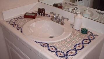 Un baño con lavamanos blanco, un espejo y salpicadero de azulejos.