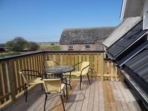 A wooden deck with a table and chairs, overlooking a rural landscape. - Mellby Ör Inn (Degerhamn)
