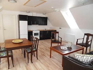 Un espacio habitable compacto con comedor, cocina y asientos.