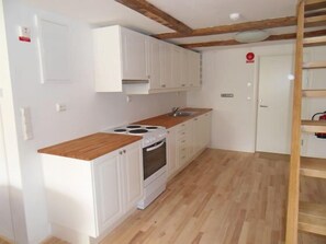 Una cocina compacta con armarios blancos, una encimera de madera y un horno empotrado.