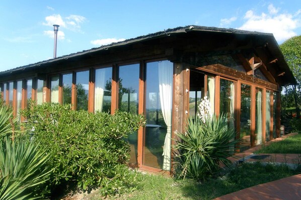 Un edificio con paredes de cristal y revestimiento de madera, rodeado de follaje.