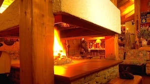 A cozy interior with a stone fireplace, wooden beams, and a rustic ambiance. - Notre Maison Eco Wellness Hotel (Cogne)