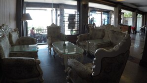 Un vestíbulo espacioso con muebles ornamentados, ventanas amplias y vistas al exterior.