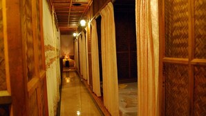 Un pasillo estrecho con paredes de madera y suelo pulido, que conduce a una habitación con cama y lámpara.