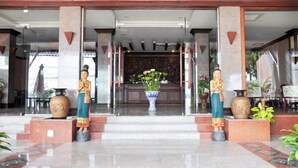 Un vestíbulo de hotel con piso de mármol, dos jarrones grandes y un mostrador de recepción.