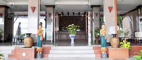 Un vestíbulo de hotel con piso de mármol, dos jarrones grandes y un mostrador de recepción.