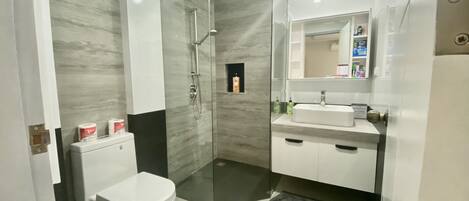 A modern bathroom with a toilet, sink, and shower.