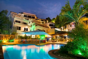 Una piscina al aire libre, sombrillas, sillones reclinables de piscina