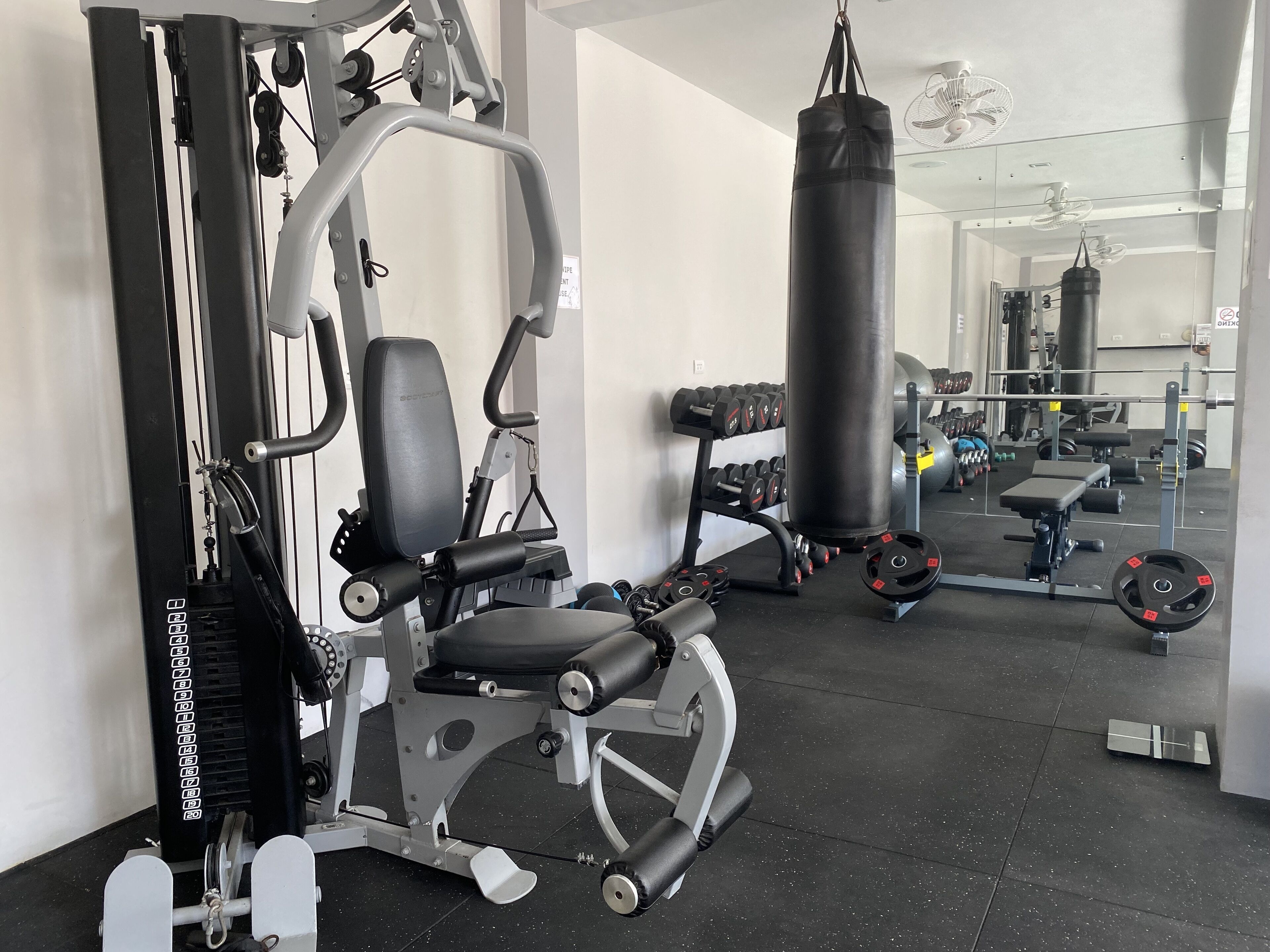 Un gimnasio con equipo de ejercicio, un saco de boxeo y accesorios para levantamiento de pesas.