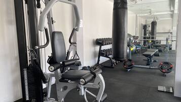 Un gimnasio con equipo de ejercicio, un saco de boxeo y accesorios para levantamiento de pesas.
