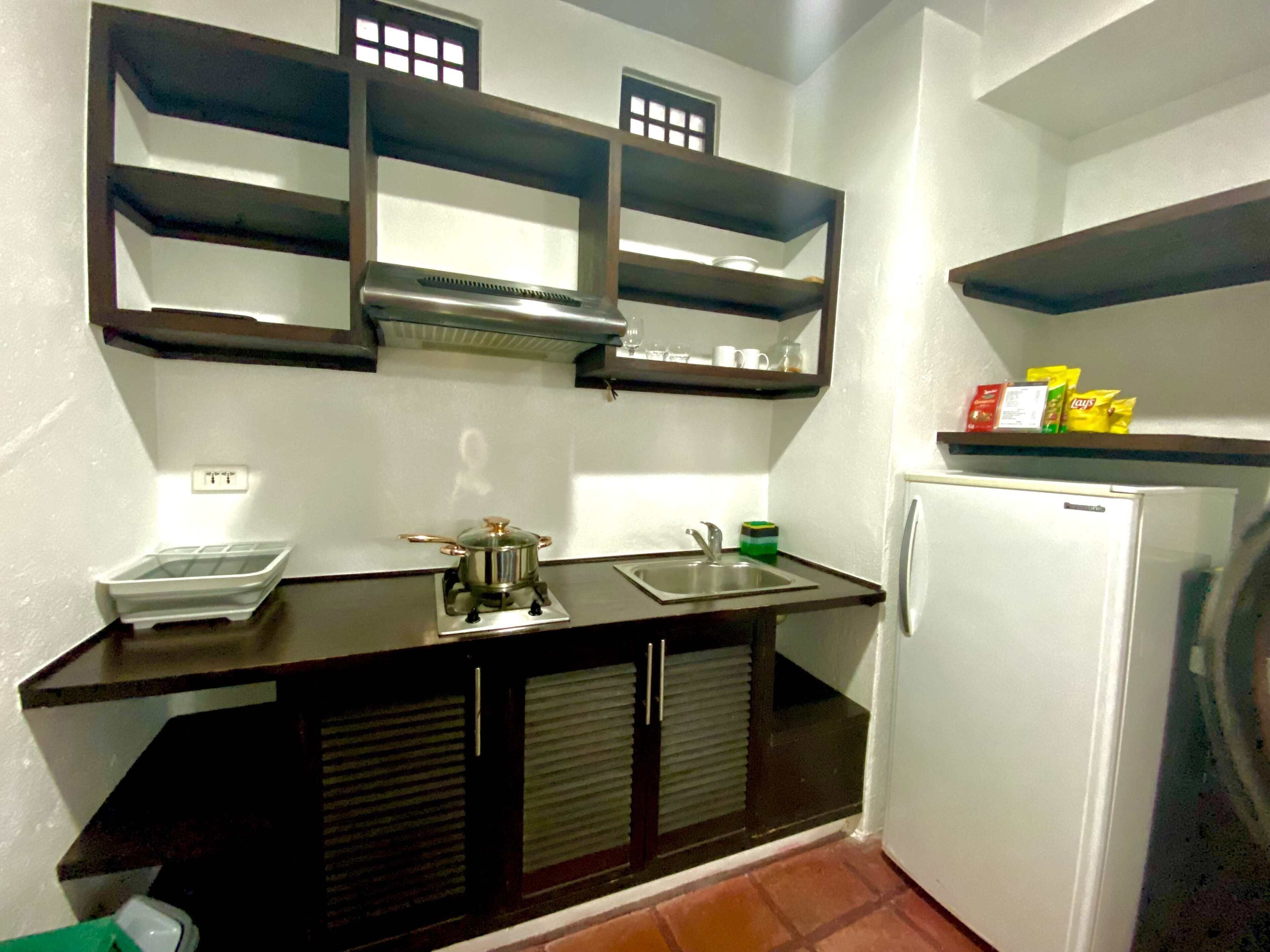 A compact kitchen with a stove, sink, and a white refrigerator.