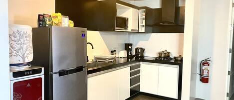Una cocina moderna con refrigerador, microondas, estufa y armarios.