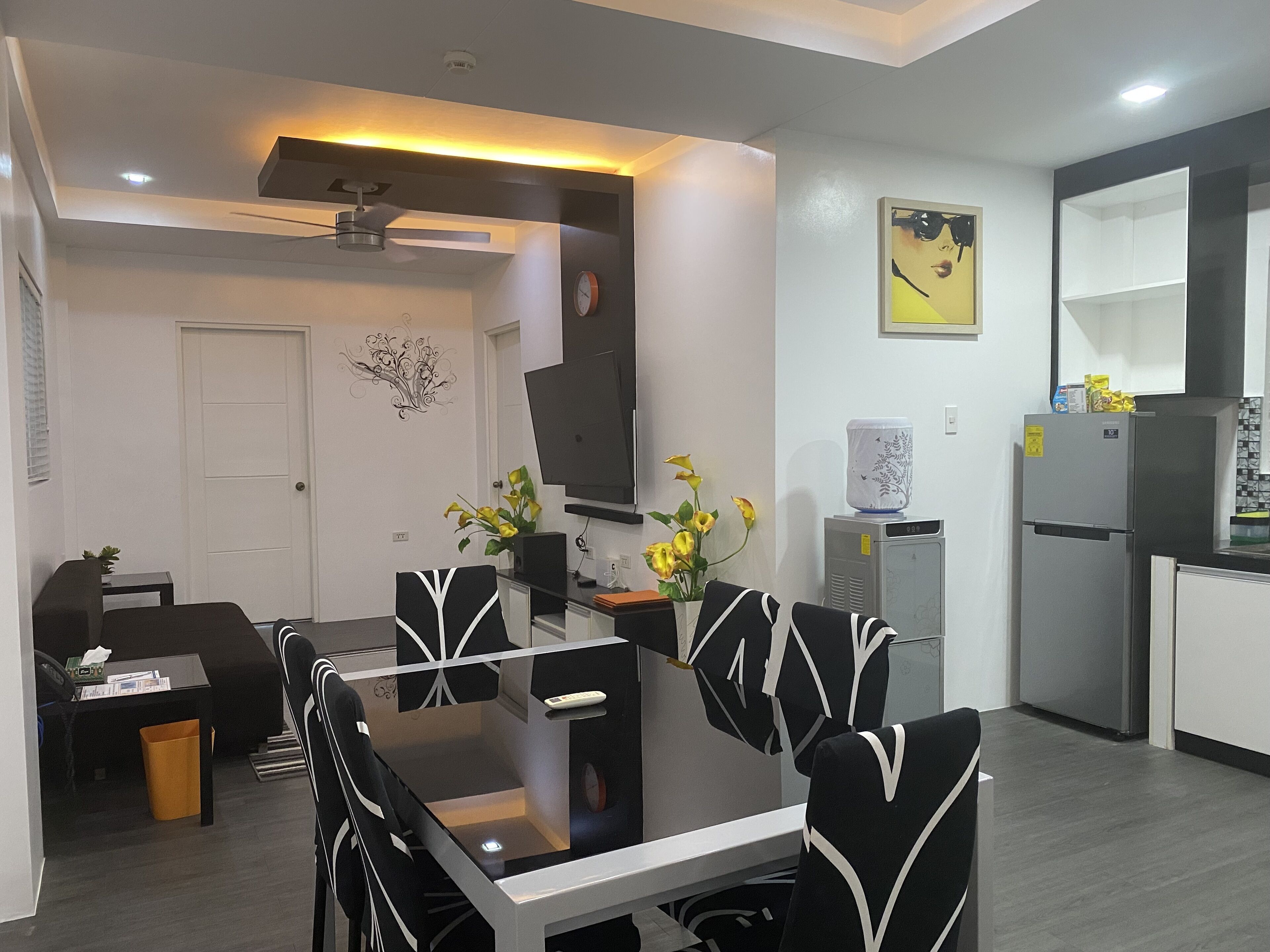 Una cocina moderna con comedor, que incluye una mesa blanco y negro, un refrigerador y un microondas.
