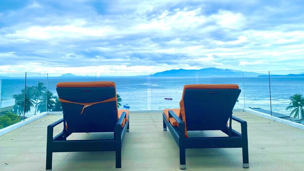 Two lounge chairs facing a body of water with a mountainous backdrop. - Lalaguna Villas Luxury Dive Resort & Spa (Puerto Galera)